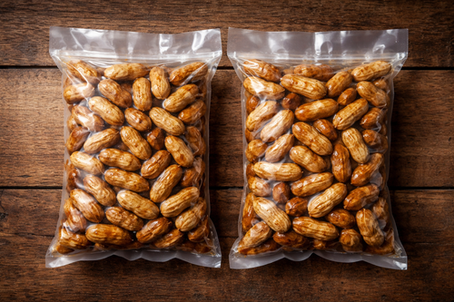 Two bags of peanuts on a wooden surface